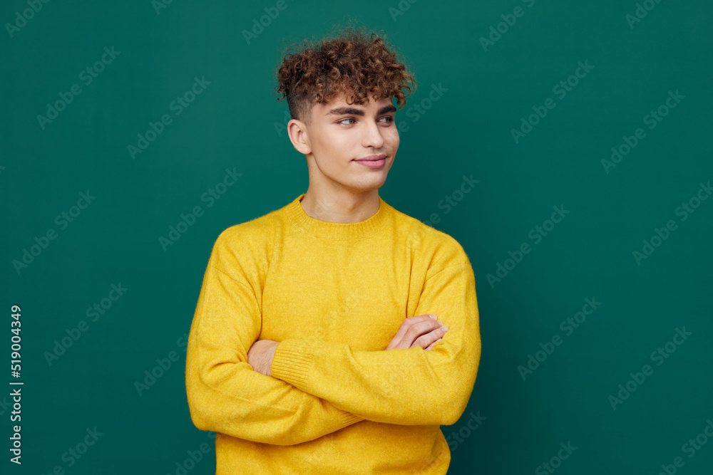 a handsome man stands on a green background in a yellow sweater and smiling pleasantly poses with his arms folded on his chest . Horizontal photo with empty space a handsome man stands on a green background in a yellow sweater and smiling pleasantly poses with his arms folded on his chest . Horizontal photo with empty space