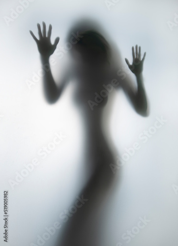 Perfect body, sexy woman shape silhouette can be seen behind a wet glass surface in bathroom.