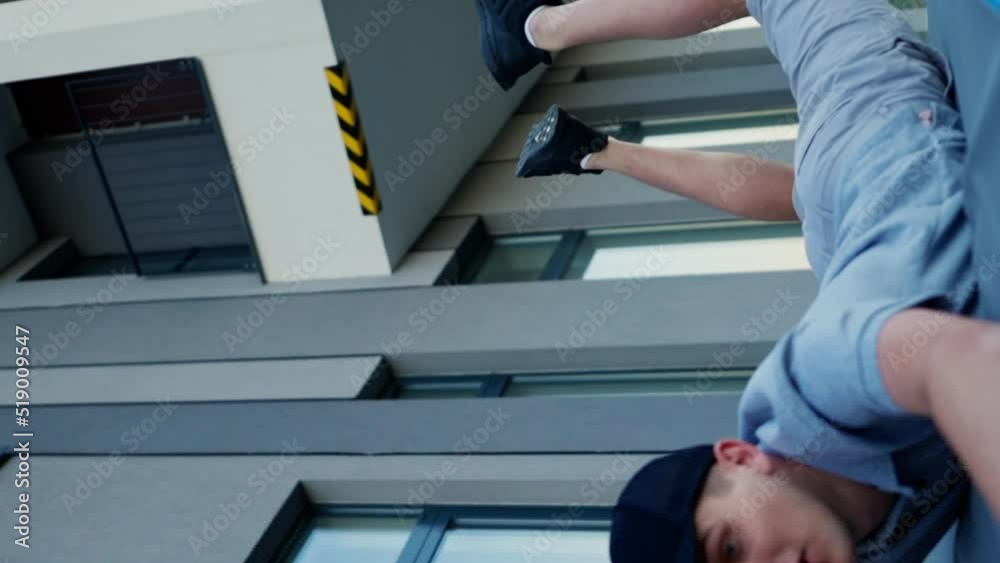 Young male courier trips and falls to the asphalt pavement along with a few parcels. vertical video Young male courier trips and falls to the asphalt pavement along with a few parcels. vertical video