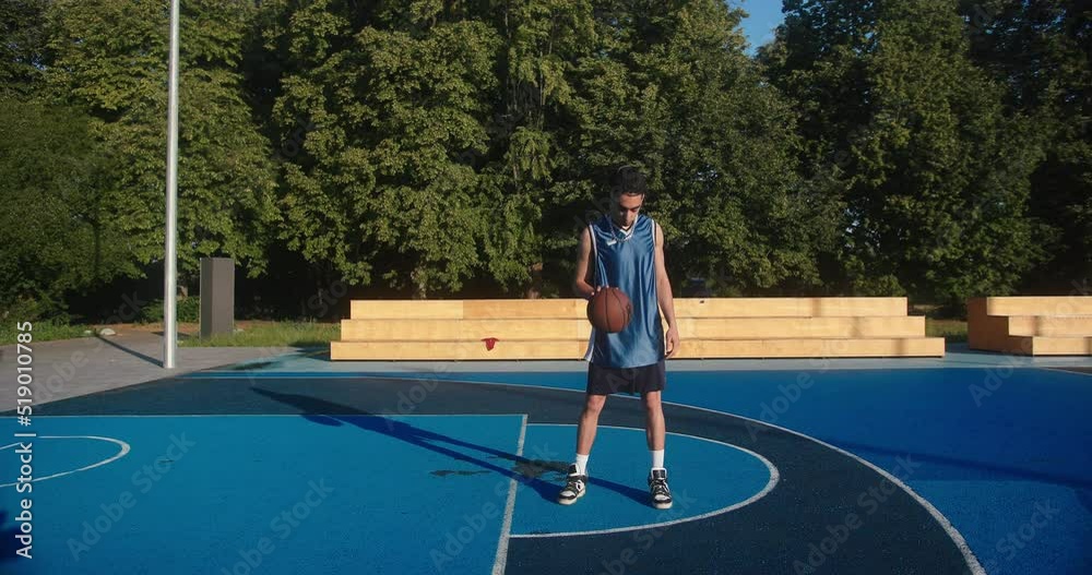 Hispanic man player stands against basket and blue sky Hispanic man player stands against basket and blue sky