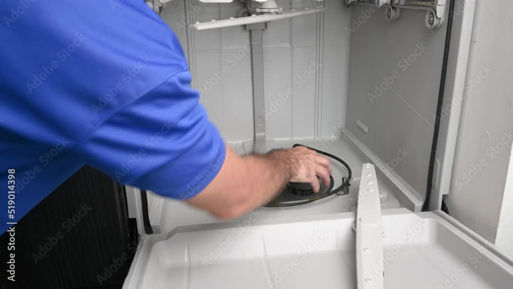 Appliance technician removing a dishwasher strainer basket Appliance technician removing a dishwasher strainer basket