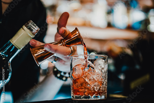 man bartender hand making negroni cocktail. Negroni classic cocktail and gin short drink with sweet vermouth, red bitter liqueur
