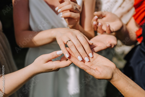 The bridesmaids hold the bride's hand and look at the beautiful gold ring on her finger. Wedding photography, concept.