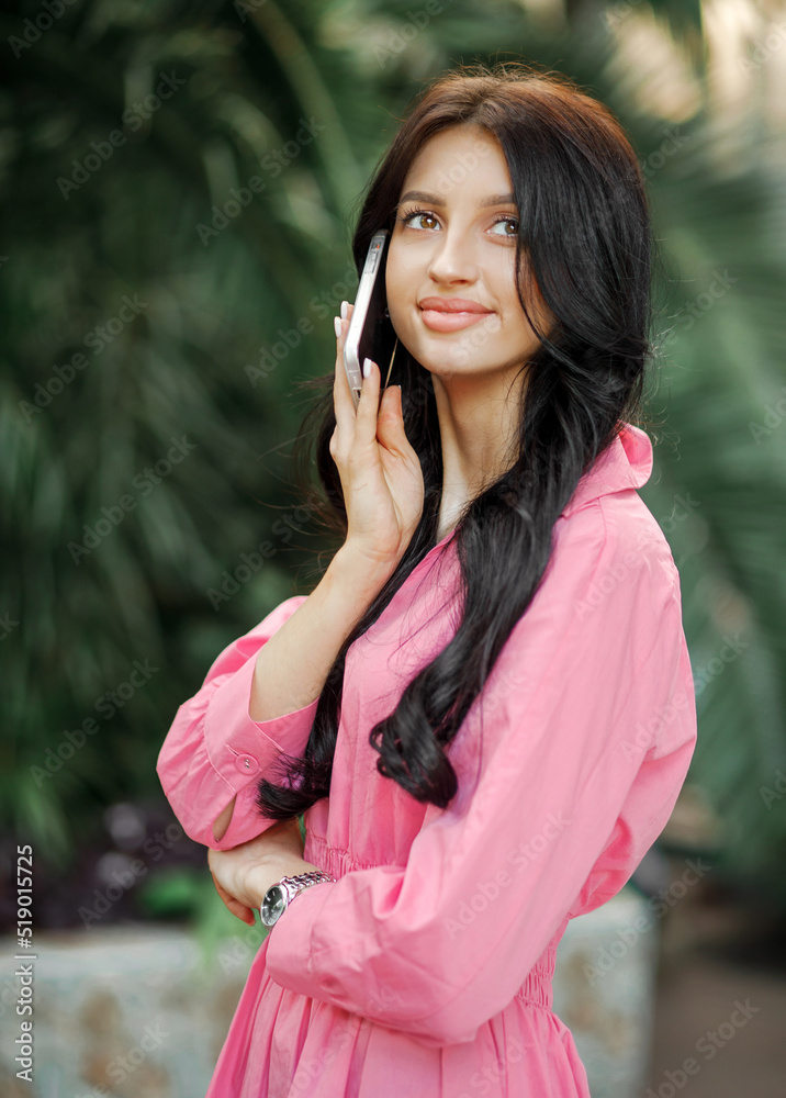 Beautiful woman in a pink dress talks on the phone Beautiful woman in a pink dress talks on the phone