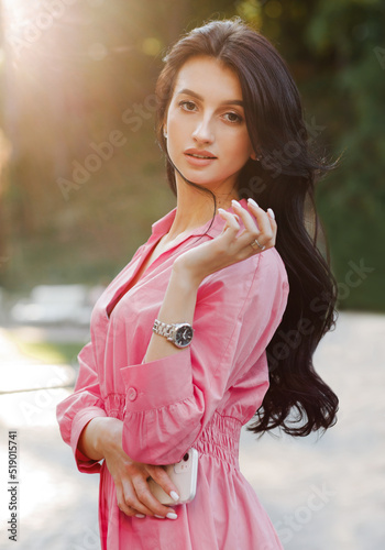 Portrait of stylish, elegant young woman with wavy hair at sunset
