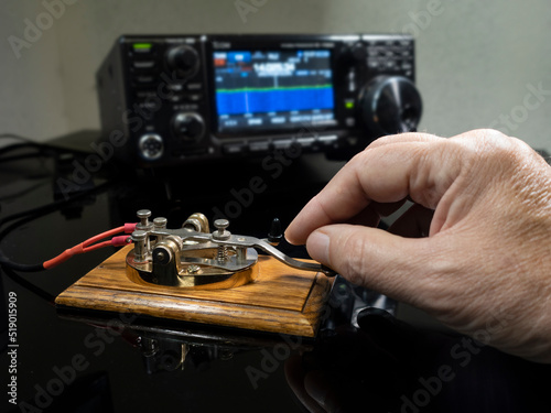 Selective focus of man's hand on a telegraph key with radio defocused in background photo
