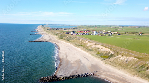 holiday in Denmark, aerial view of the cliff along the North Sea between the famous Bovbjerg Fyr lighthouse and the village Ferring with its white church and the Ferring Sø Fjord in the background photo