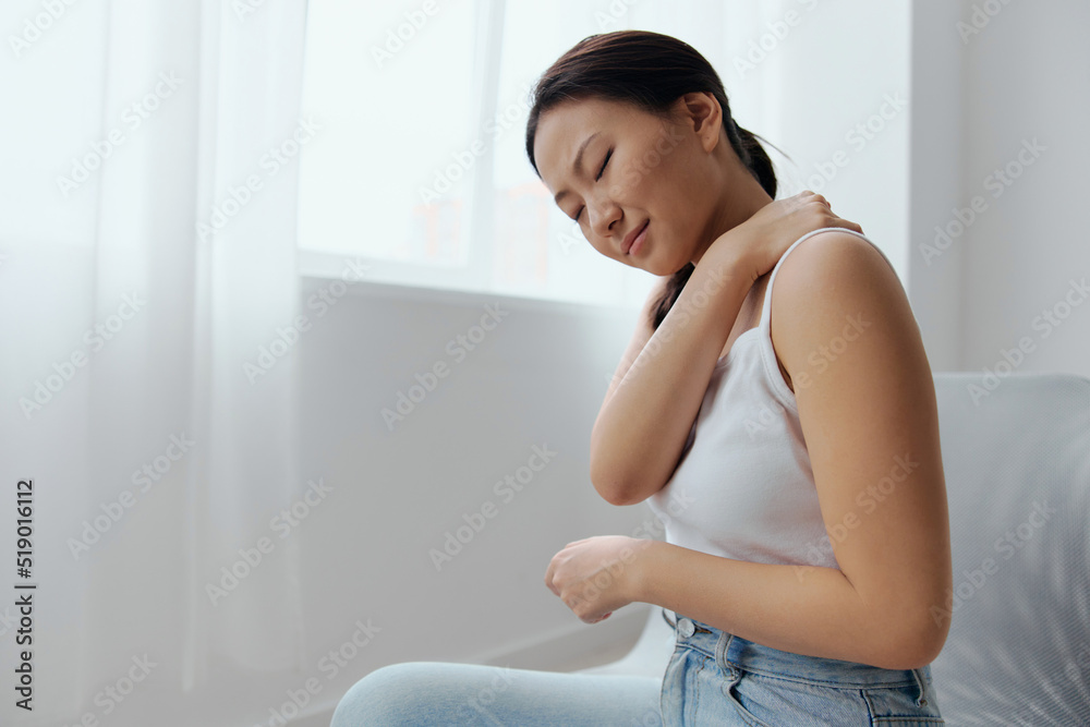 Suffering from neuralgia after sleeping in the wrong position tanned beautiful young Asian woman touching painful shoulder at home living room. Injuries Poor health Illness concept. Cool offer Banner