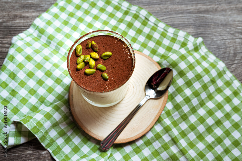 Dessert tiramisu with pistachios sprinkled with cocoa powder. View from slightly above.