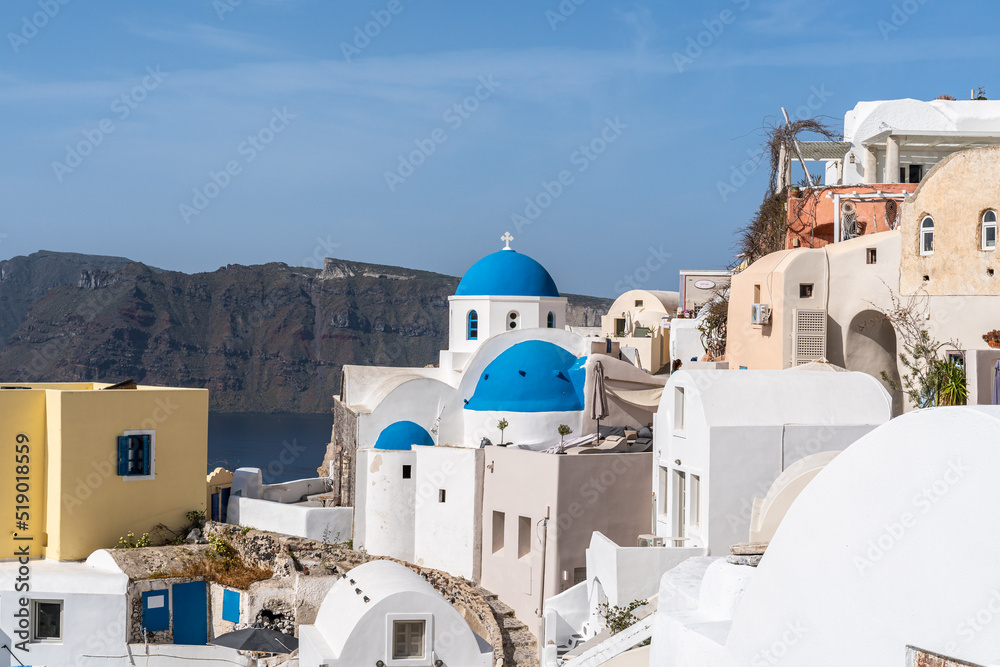 View of Oia village in Santorini with traditional white houses and blue domes churches, Greece