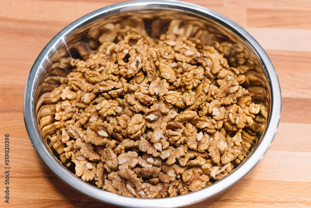 Peeled walnuts, large quantities in a metal bowl on the table. Peeled walnuts, large quantities in a metal bowl on the table.