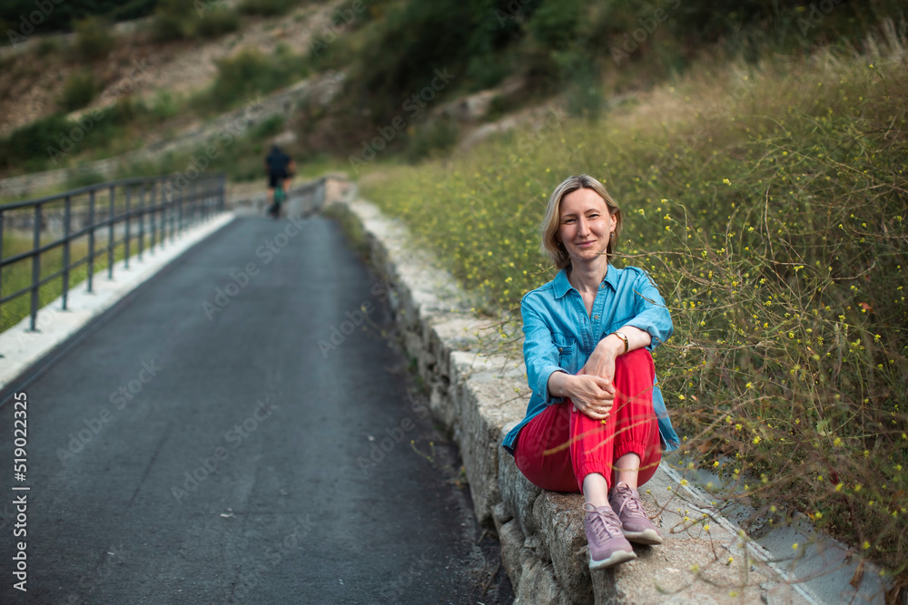 A woman is resting on the side of the road. A woman is resting on the side of the road.