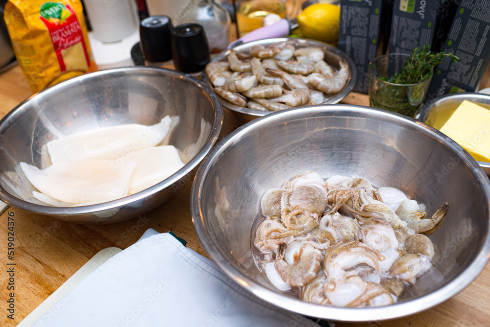 Raw seafood in a metal bowl. Cooking preparations. Bowl with uncooked shrimp. Bowl with raw squid. Table with billets. Raw seafood in a metal bowl. Cooking preparations. Bowl with uncooked shrimp. Bowl with raw squid. Table with billets.