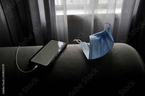 Mobile phone and mask on a sofa 