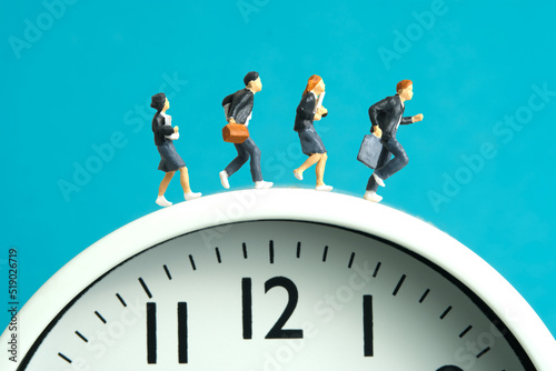 Miniature people toy figure photography. End and start of school concept. Pupils running above white clock isolated on blue background