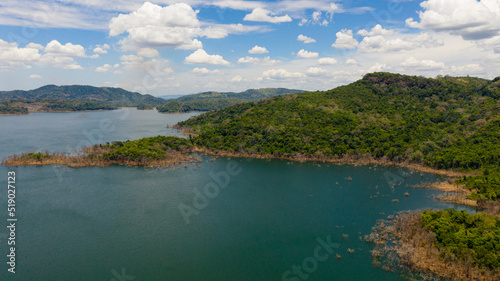 Aerial view of lake among mountains covered rainforest and blue sky with clouds. Kalu Ganga Reservoir, Sri Lanka.