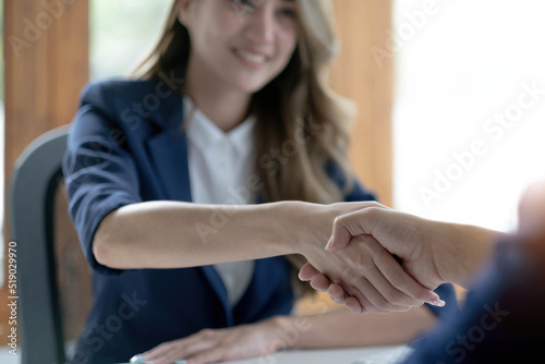 Closeup of unrecognizable happy businesswoman shaking hands with business partner after signing contract during meeting in office.