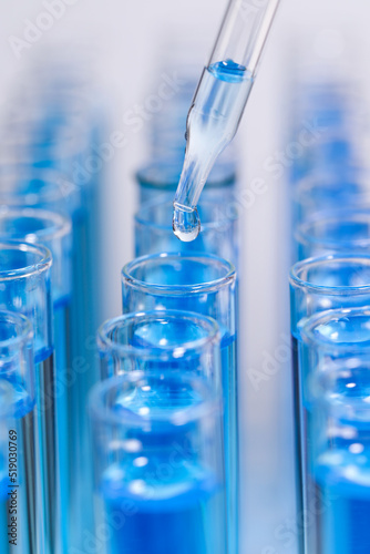 Cuadro en lienzo Dripping reagent into test tube with blue liquid on light background, closeup