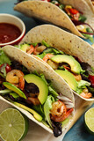 Delicious tacos with shrimps, avocado and lime on turquoise table, closeup
