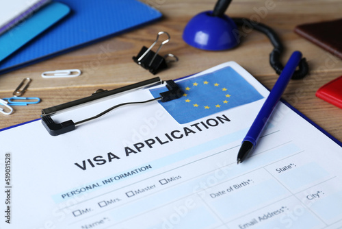 Visa application form for immigration to European Union and stationery on wooden table, closeup