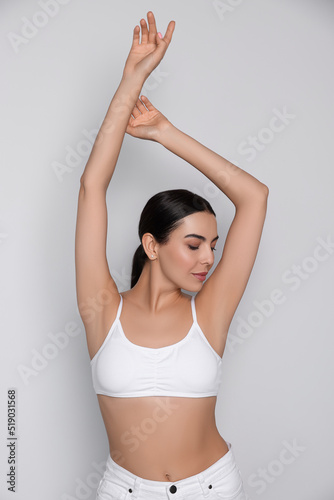 Young woman showing smooth skin after epilation on white background