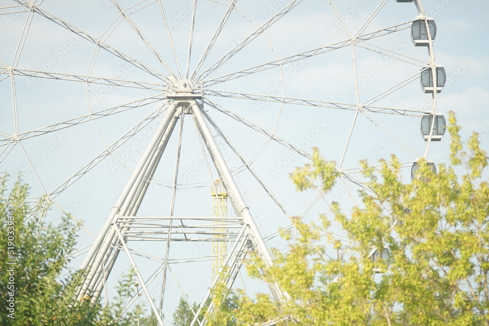 Obraz premium Horizontal full-color photo. Urban landscape. Geometric semicircular composition. The attraction is a Ferris wheel.