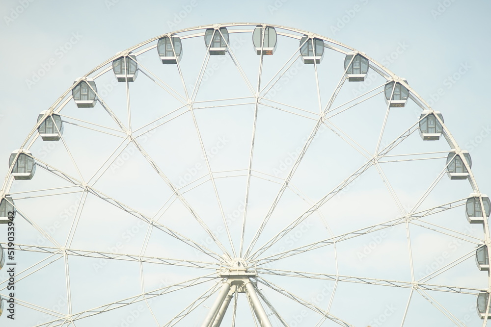 Obraz premium Horizontal full-color photo. Urban landscape. Geometric semicircular composition. The attraction is a Ferris wheel.