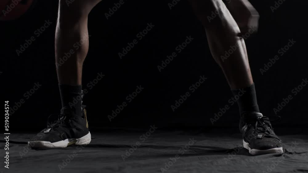 Basketball player bouncing a ball. African american sports man practicing against black background.. Basketball player bouncing a ball. African american sports man practicing against black background..