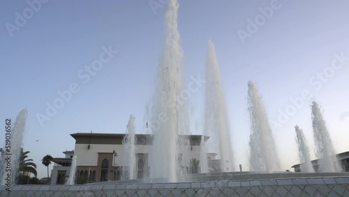 Wide shot, water jet in action in Casablanca's new Mohammed 5 Square fountain, Wilaya city hall with its clock tower in the background. photo
