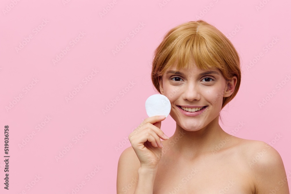 horizontal photo of a happy, sophisticated woman with blonde hair gathered back, standing on a pink background, holding a cotton pad in her hand and smiling sweetly advertising it horizontal photo of a happy, sophisticated woman with blonde hair gathered back, standing on a pink background, holding a cotton pad in her hand and smiling sweetly advertising it