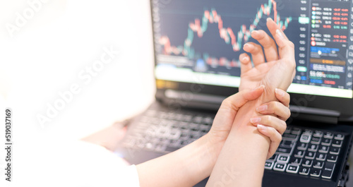Asian woman holding her sore hand on wrist close-up. Pain from using a computer. Office syndrome hand pain by working in front of the laptop.