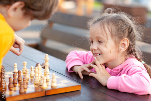 little sister smiling watching her brother make a move in chess