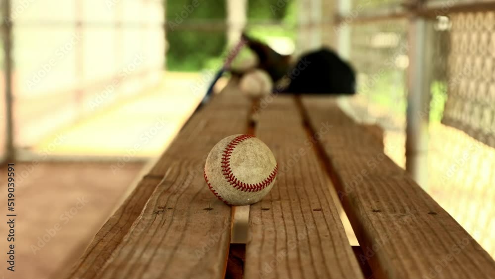 Player hand reaches in to grab baseball from dugout bench Player hand reaches in to grab baseball from dugout bench