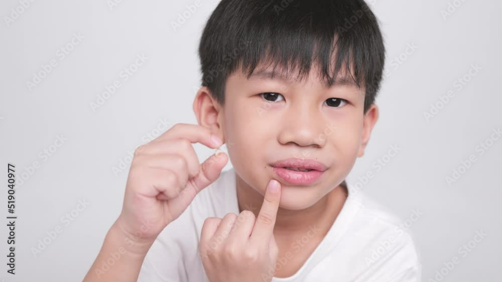 Asian kid holding the first fallen baby milk teeth while the second tooth loses and bends in his mouth. A happy boy proudly smiles at his dental care. Asian kid holding the first fallen baby milk teeth while the second tooth loses and bends in his mouth. A happy boy proudly smiles at his dental care.