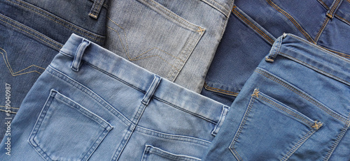 Various blue shades and sizes of pairs of denim jeans back side 