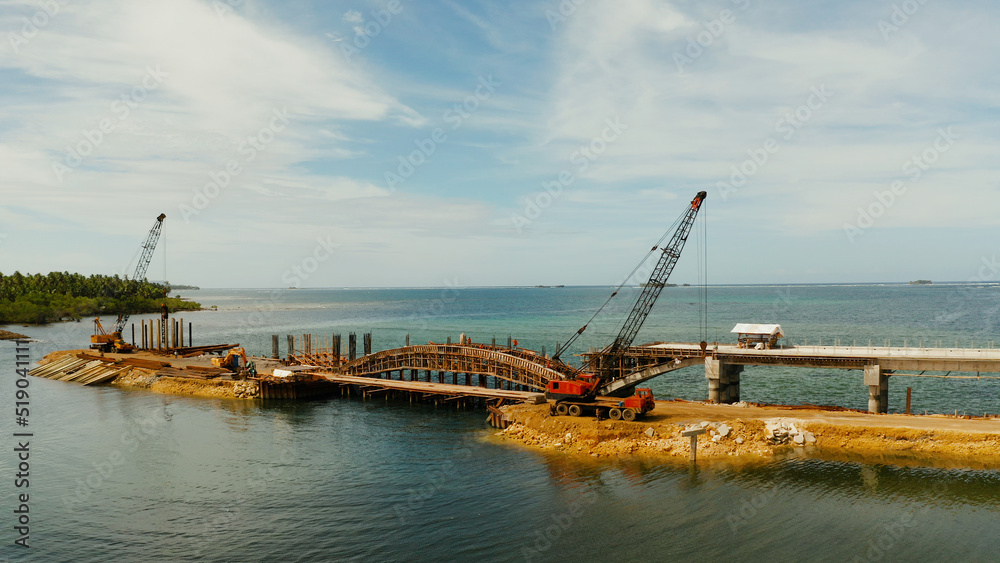Pile hammer working on construction site. Bridge under construction over the sea bay connecting the two parts of Siargao island.