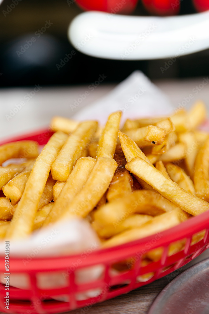 Red basket with delicious french fries on a wooden table Red basket with delicious french fries on a wooden table