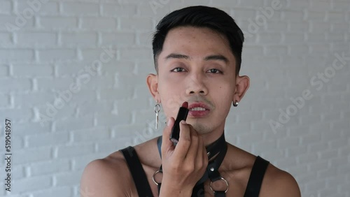 A bisexual guy paints his lips and looks passionately into the camera. A transgender man has the right to be inclusive and to be free of self-identity. The concept of lgbt community in the world. photo