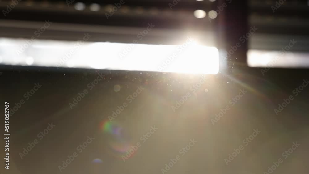 Hand passing in front of camera moving dust particles against sunlight. Gimbal, blur