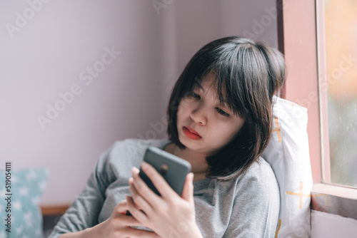Woman looking at phone with a despairing expression.