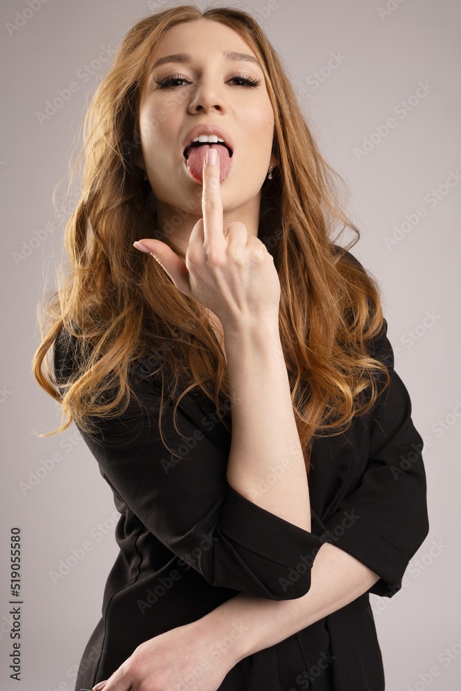 portrait of redhead business woman in black suit lick middle finger - fuck symbol portrait of redhead business woman in black suit lick middle finger - fuck symbol