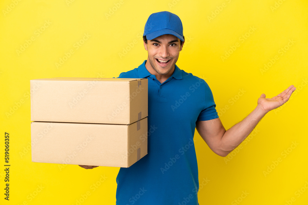 Delivery man over isolated yellow wall with shocked facial expression Delivery man over isolated yellow wall with shocked facial expression