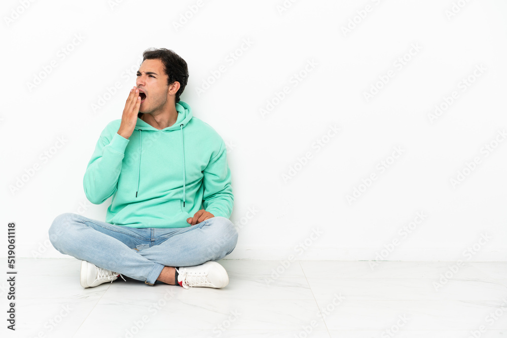 Caucasian handsome man sitting on the floor yawning and covering wide open mouth with hand Caucasian handsome man sitting on the floor yawning and covering wide open mouth with hand