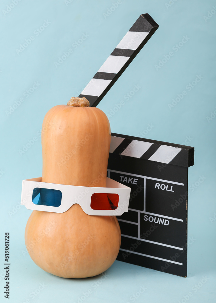 Decorative thematic still life. Pumpkin in 3d glasses with clapperboard on blue background