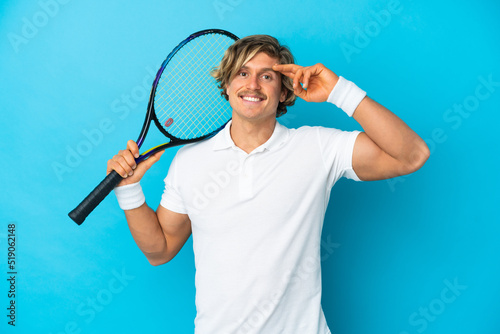 Young blonde man isolated on blue background playing tennis © luismolinero