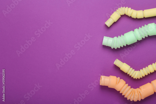 Many Antistretch pop tube toys on purple background with copy space. Top view