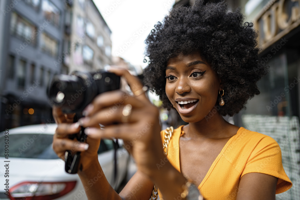 Smiling African american woman using professional camera at a street Smiling African american woman using professional camera at a street
