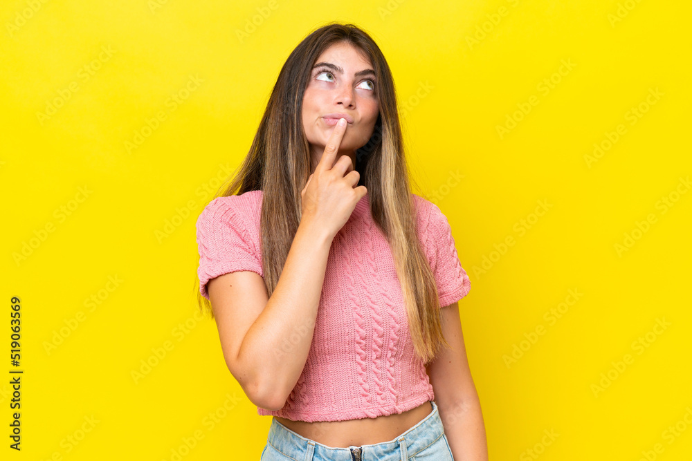 Young caucasian woman isolated on yellow background having doubts while looking up Young caucasian woman isolated on yellow background having doubts while looking up