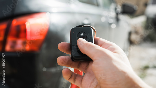 Close-up of driver's hand pressing button on car alarm remote control outdoors