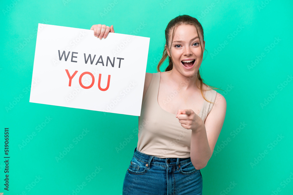 Young caucasian woman isolated on green background holding We Want You board and pointing to the front Young caucasian woman isolated on green background holding We Want You board and pointing to the front